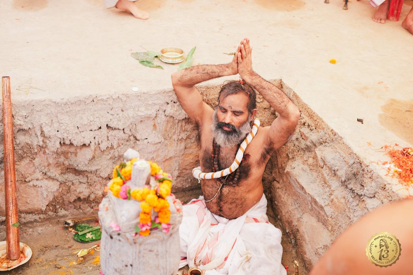A priest performing puja within the foundation pit during the Shadadhara ceremonies